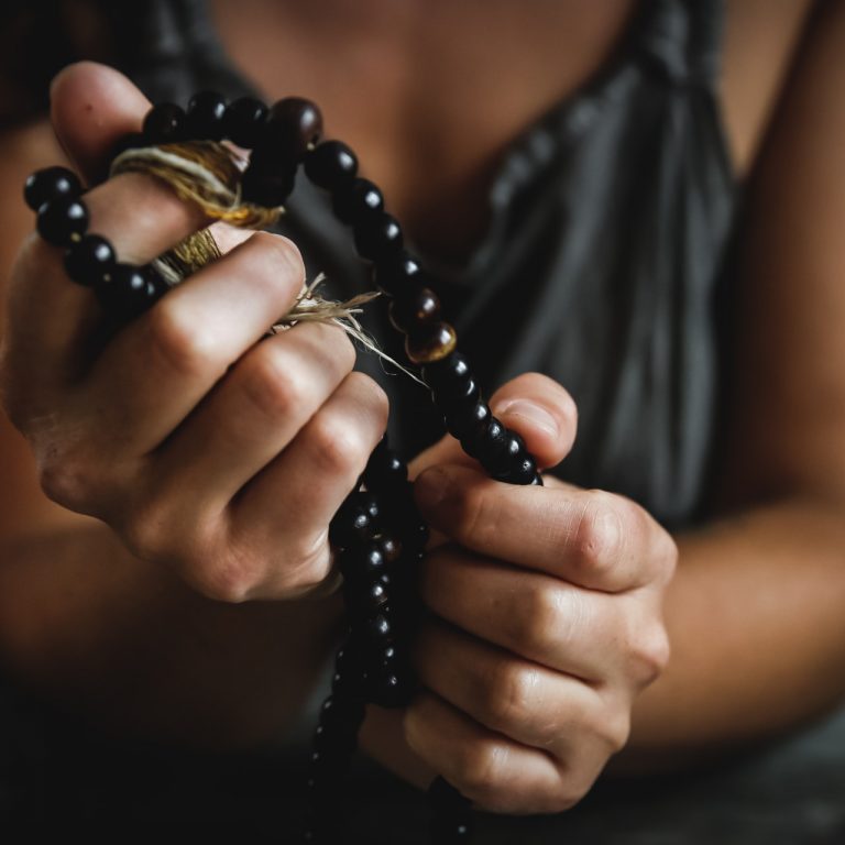 hands holding a black rosary